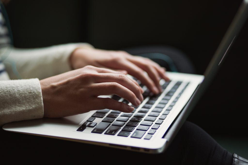 Hands typing on a laptop